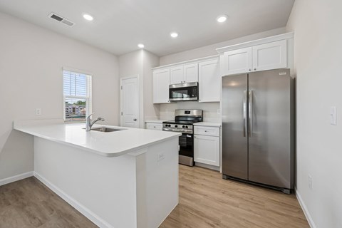 A kitchen with white cabinets and a stainless steel refrigerator.