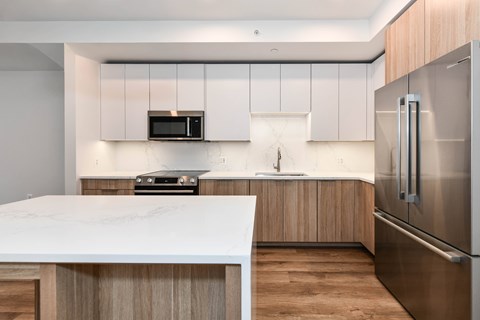 A modern kitchen with a white marble countertop and stainless steel appliances.