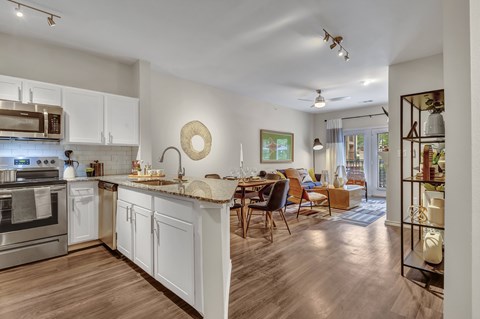 A modern kitchen with white cabinets and a wooden floor.