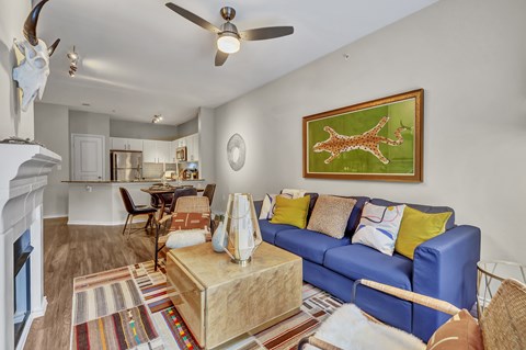 A living room with a blue couch and a painting of a giraffe.