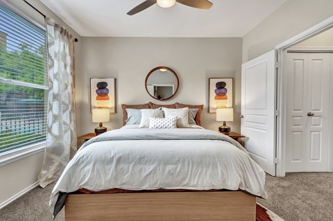 A bedroom with a large bed, a round mirror, and two lamps.