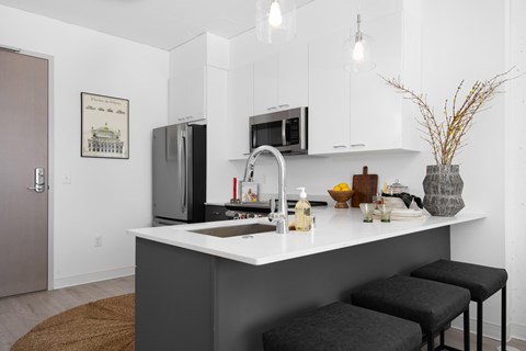 A kitchen with a white counter and a black fridge.