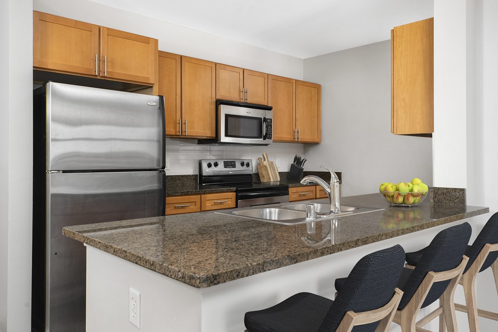 a kitchen with a granite counter top and stainless steel appliances at The Bayshore Place Apartments in Glendale, WI