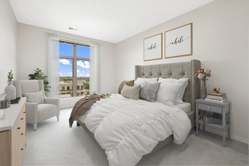Bedroom with furniture and a large window at The Bayshore Place Apartments in Glendale, WI