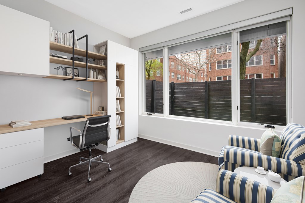 a living room with a large window and a desk with a chair