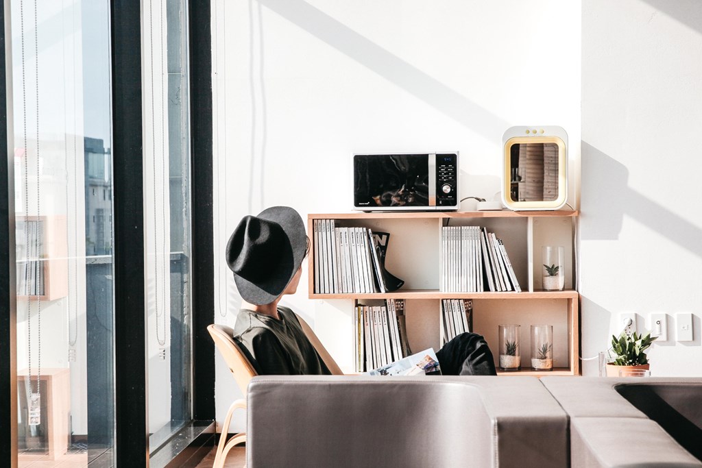 a person sitting in a chair in a room with a book shelf and a window