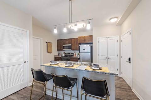 A kitchen with a table and chairs in front of a refrigerator and microwave.