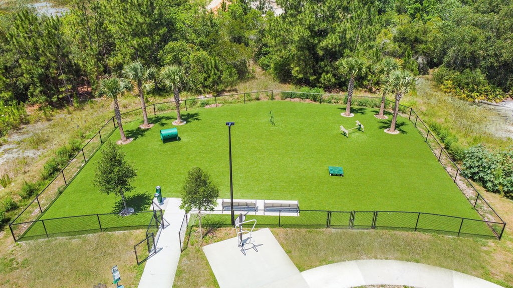 Dog park at westerly apartments with trees, grass, and agility equipment