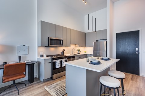 A modern kitchen with a white island and a black refrigerator.