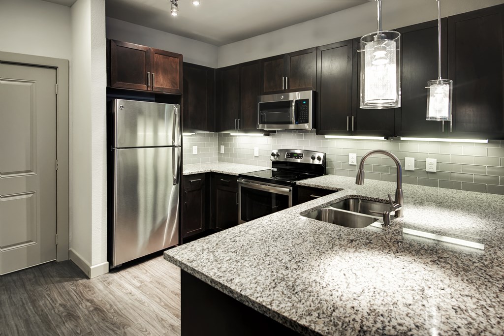 a kitchen with granite counter tops and a stainless steel refrigerator