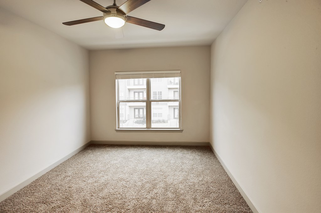 an empty room with a ceiling fan and a window