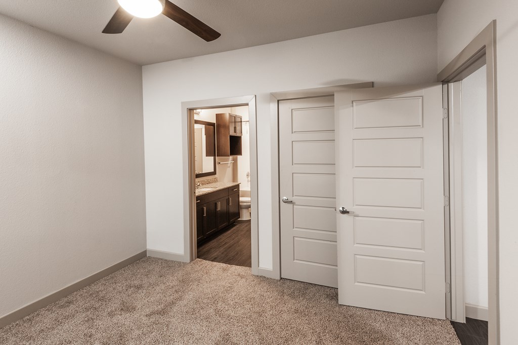 an empty bedroom with an open door to a bathroom