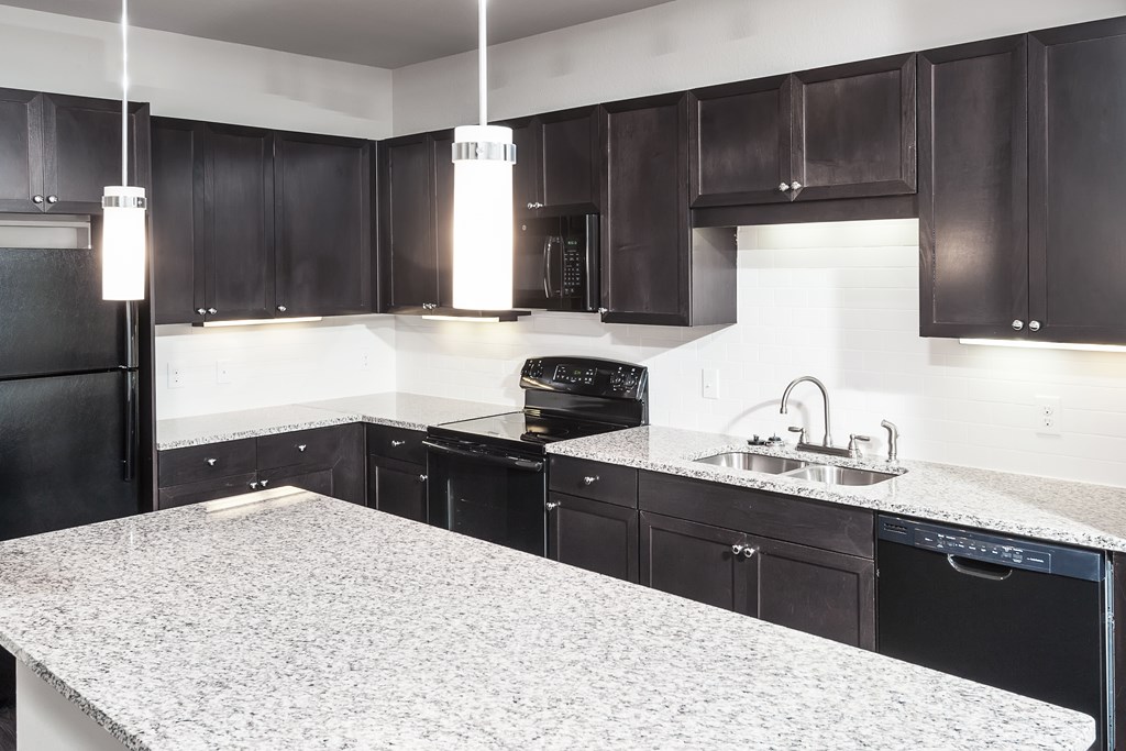 a kitchen with black and white granite counter tops and black appliances