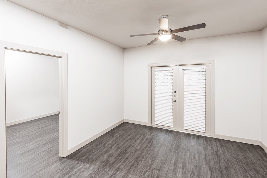 an empty living room with white walls and a ceiling fan