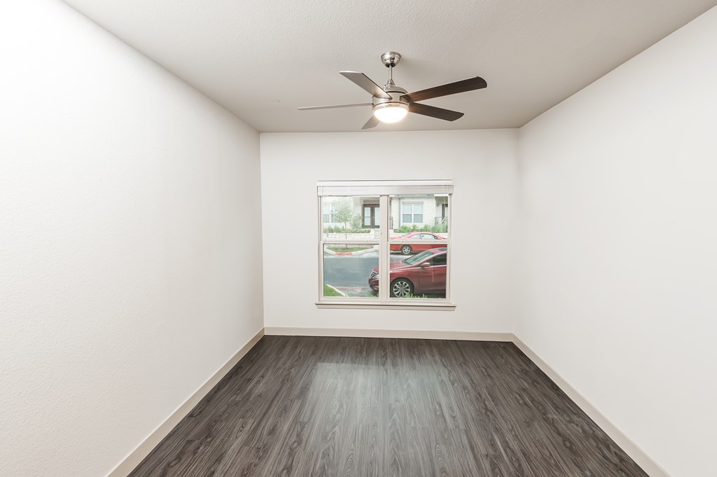an empty room with a window and a ceiling fan