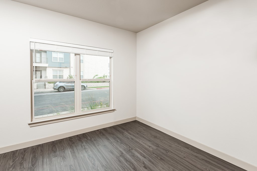 an empty room with a large window and wood floors