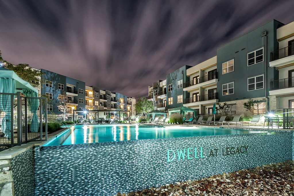 a swimming pool at night in front of an apartment building