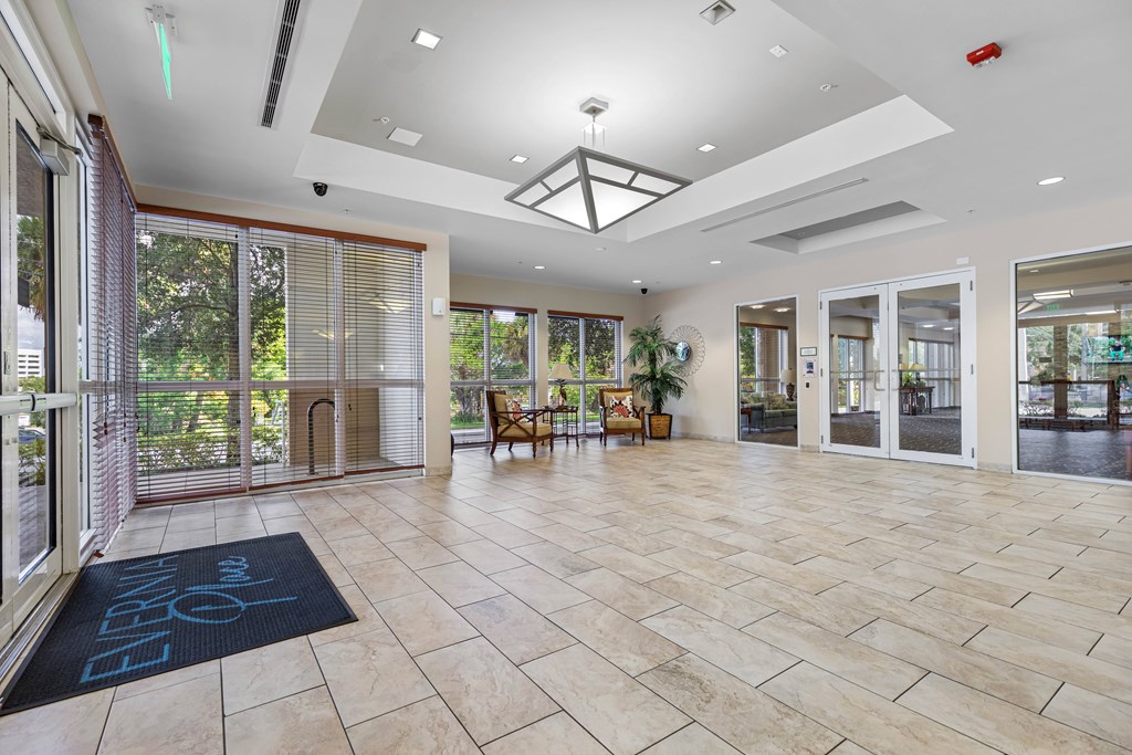 A spacious lobby with a tiled floor and a glass wall.