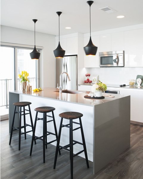 A kitchen with a white counter and bar stools.