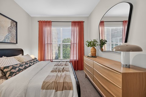 A bedroom with a large bed and a mirror on the wall.