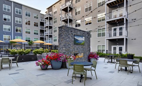 A patio with tables and chairs and a fireplace.