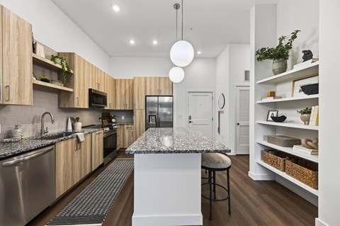 A modern kitchen with a granite countertop and stainless steel appliances.