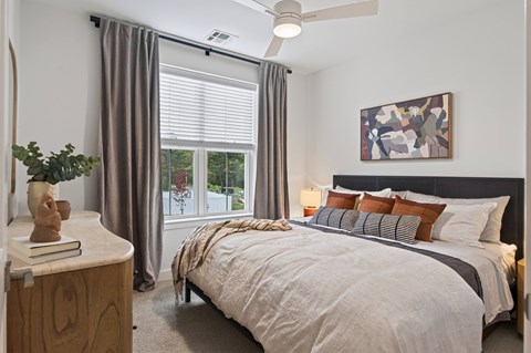 A bedroom with a large bed and a window with curtains.