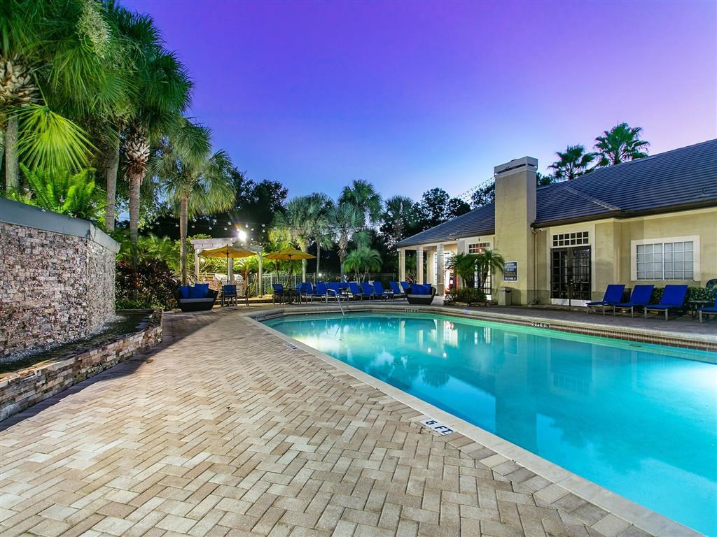a swimming pool is next to a house with blue chairs