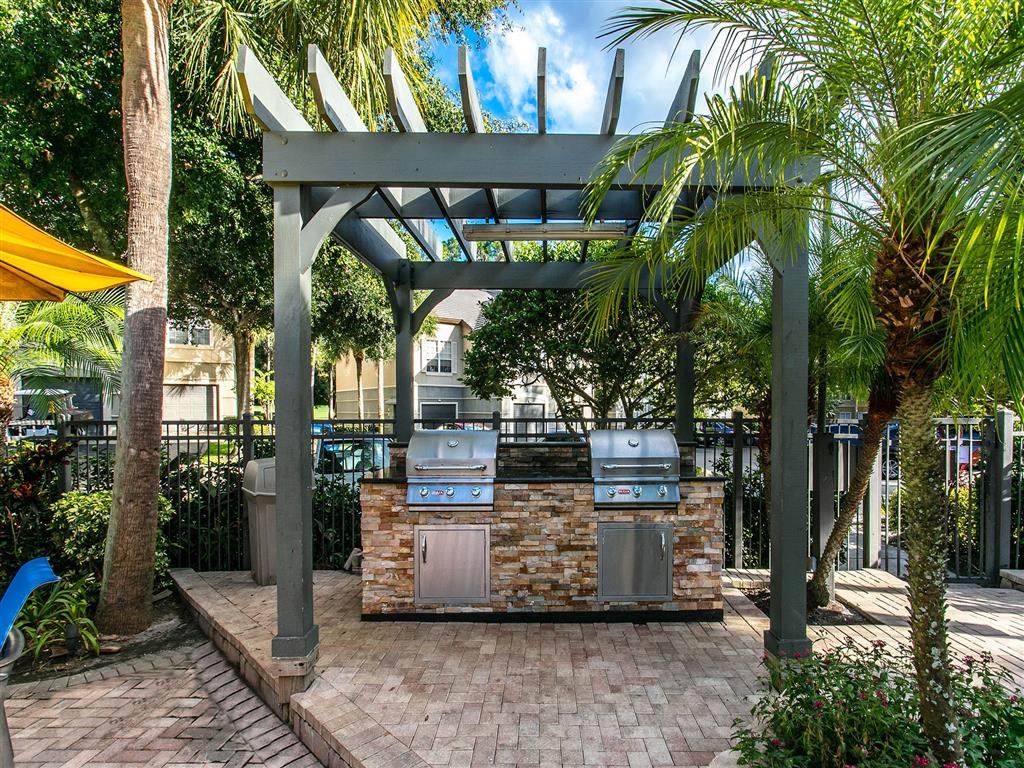 a bbq area with two grills and palm trees