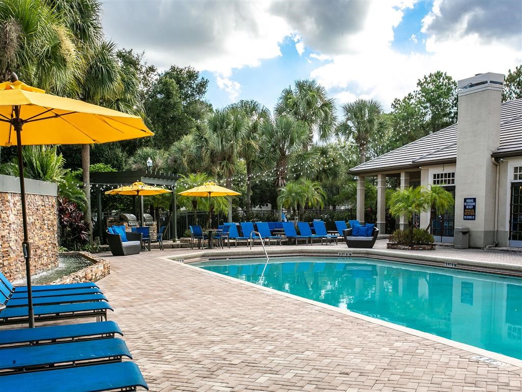 a swimming pool with blue chairs and yellow umbrellas