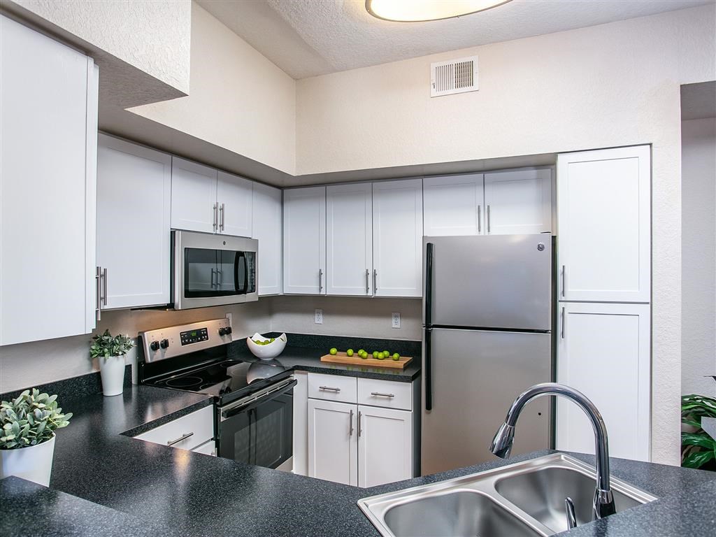 a kitchen with white cabinets and a stainless steel refrigerator