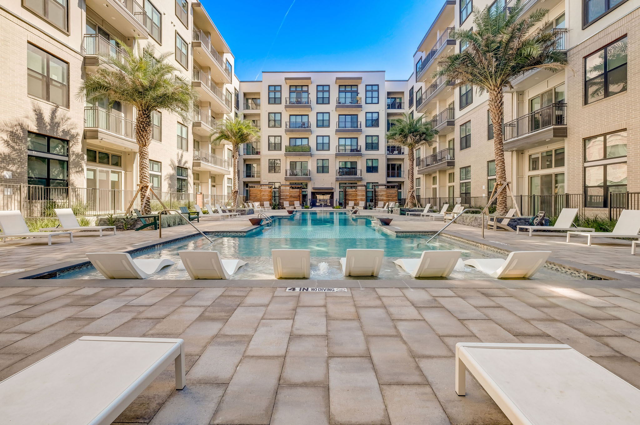 a large swimming pool in an apartment building with palm trees
