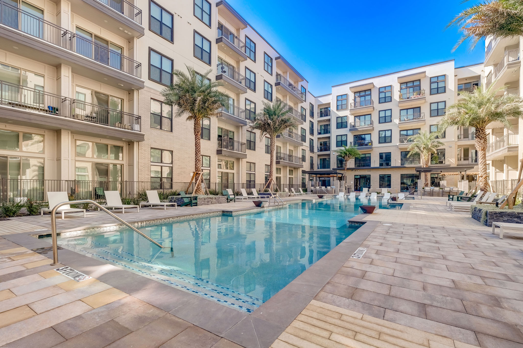 a large swimming pool in front of an apartment building