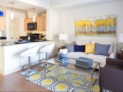 A modern living room with a white couch and a yellow and blue rug.