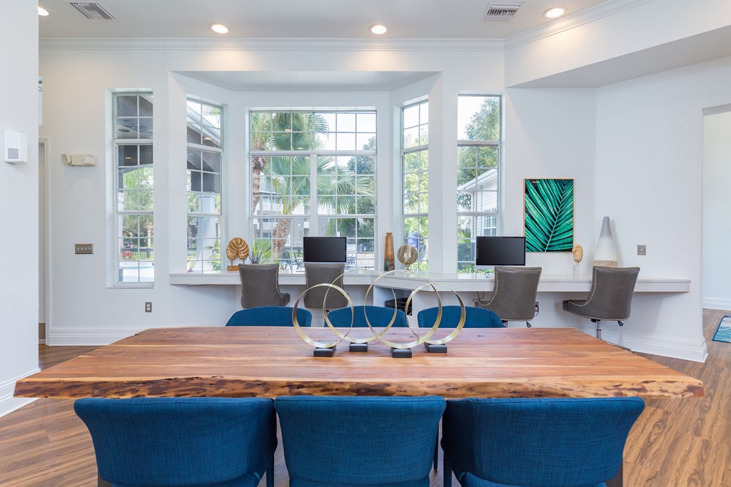 a large wooden table with blue chairs and a large window in the background