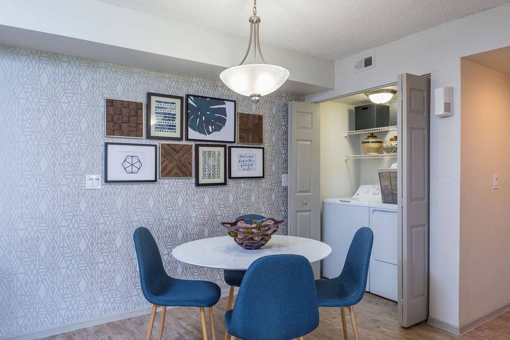 a dining area with a white table and four blue chairs