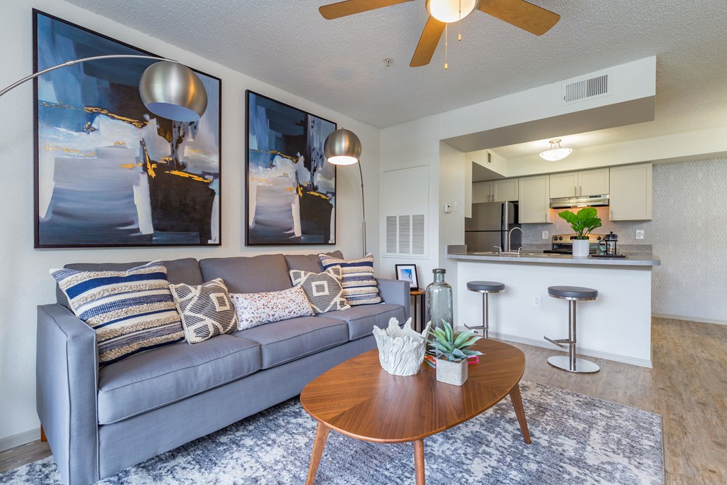 a living room with a couch coffee table and a kitchen in the background
