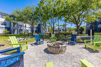 a fire pit surrounded by blue and green adirondack chairs