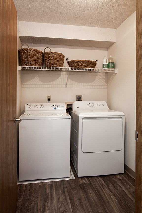 a white washer and dryer in a small laundry room with baskets on top