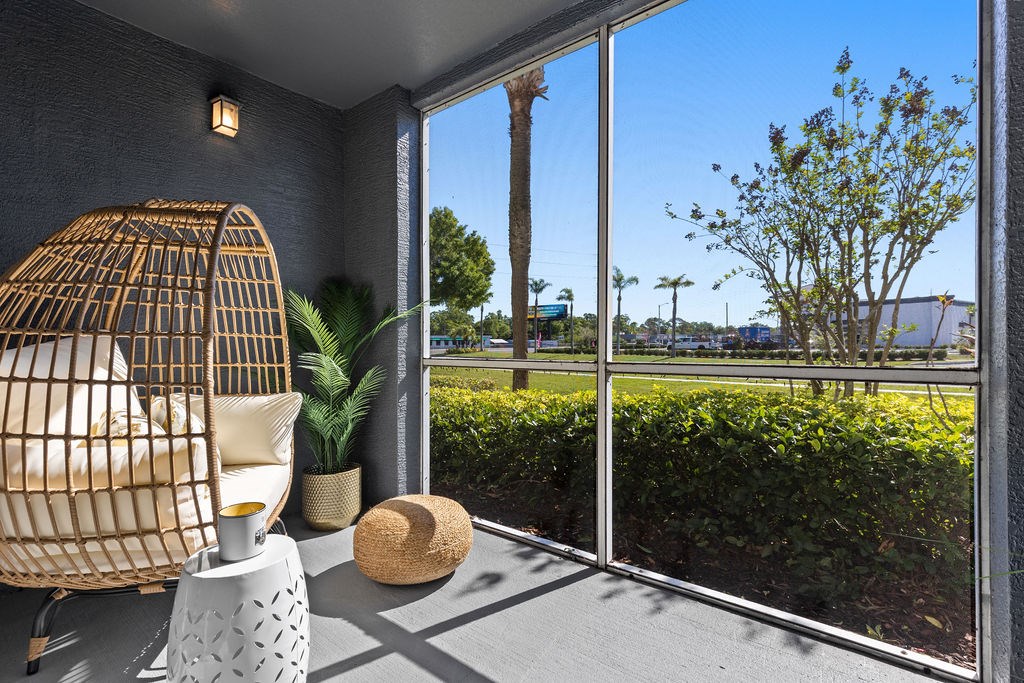 a room with a large window and a rattan chair