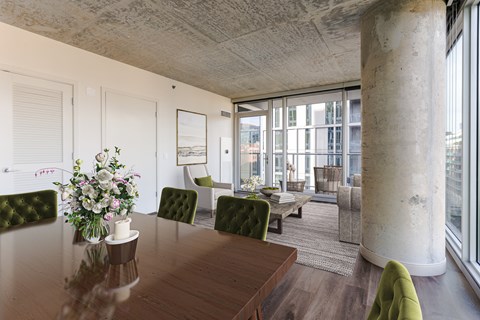 A dining room with a wooden table and green chairs.