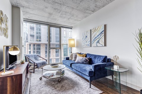 A living room with a blue couch and a glass coffee table.
