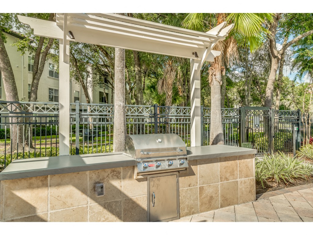 an outdoor kitchen with a grill and a white canopy