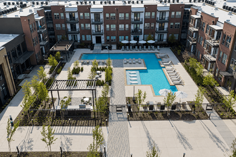 An aerial view of a pool surrounded by buildings and trees.