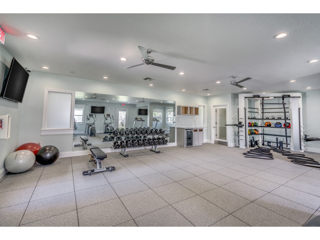 the home gym has plenty of equipment and a large screen tv