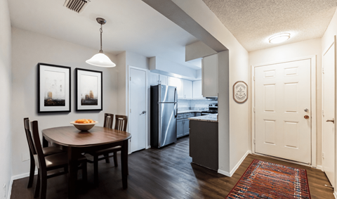 A kitchen with a table and chairs in the foreground and a refrigerator in the background.