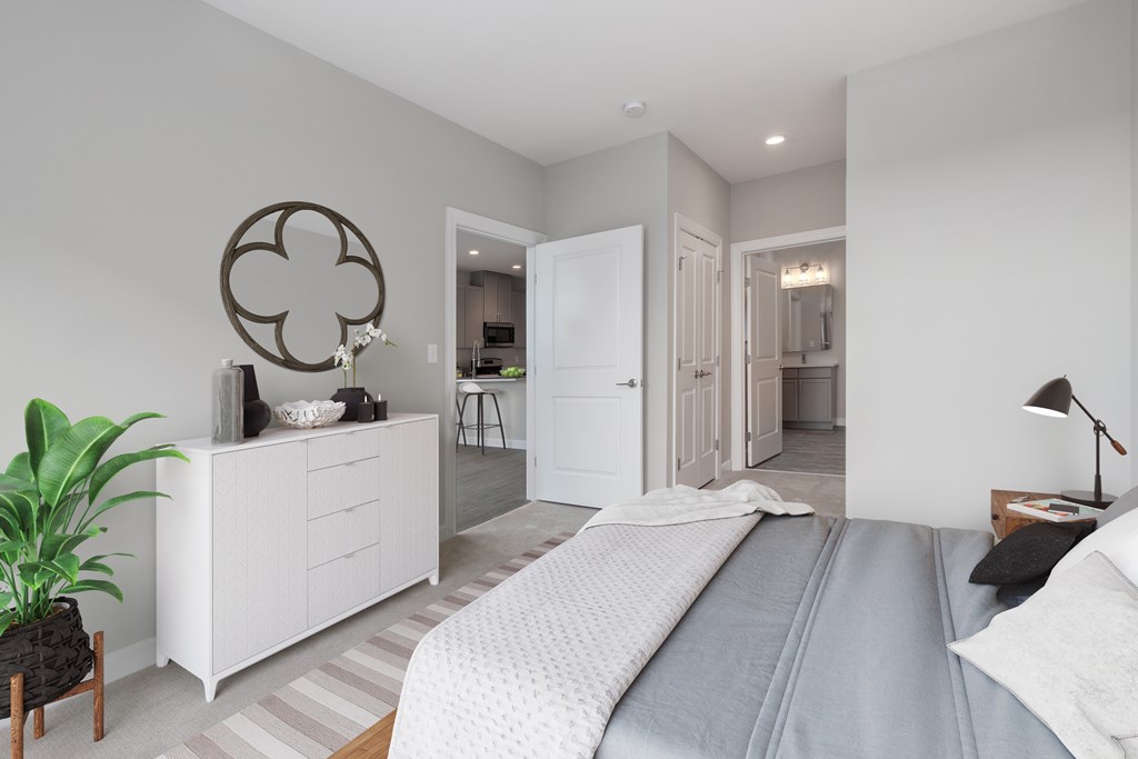 A bedroom with a large bed and a white dresser with a round mirror above it.
