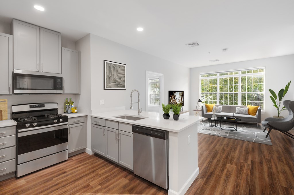 A modern kitchen with stainless steel appliances and wooden floors.