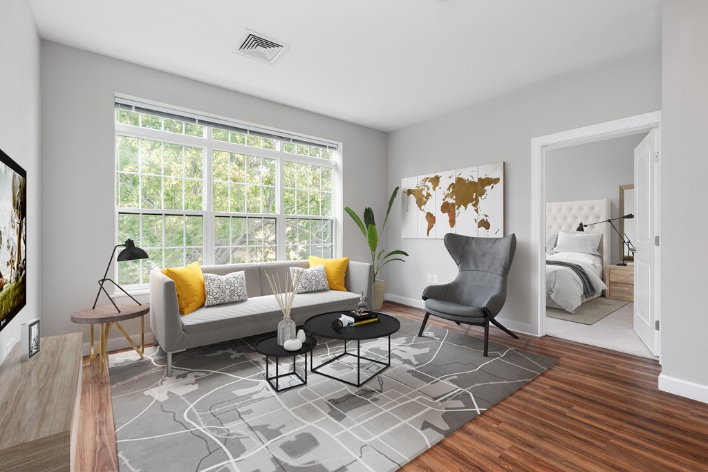 A living room with a grey couch, a grey armchair, a black coffee table, and a grey rug.
