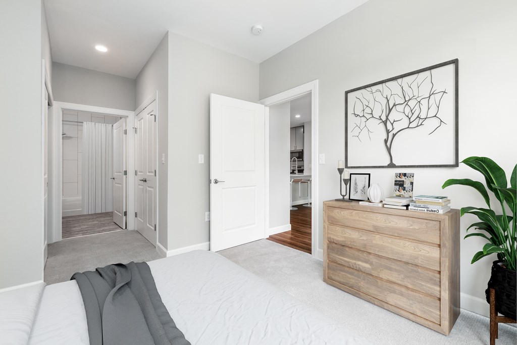 A bedroom with a bed, a dresser, and a plant.